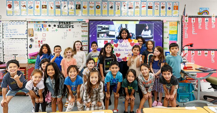 La educadora de Journey, Maria Vincent, sonríe con su curso de primer año en la escuela primaria Kaʻūmana.