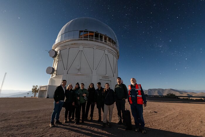 Journalists and staff outside the Víctor M. Blanco 4-meter Telescope at night.